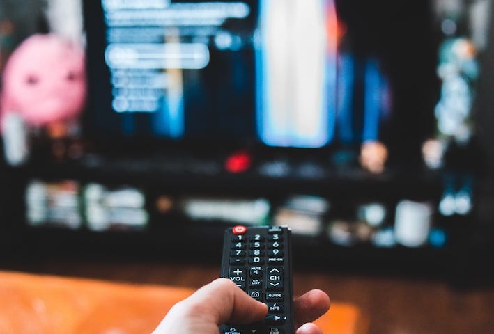 IMAGE: A hand pointing a remote towards an out of focus TV set