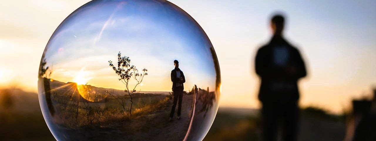 A blurred man in the background with his reflection shown in a bubble