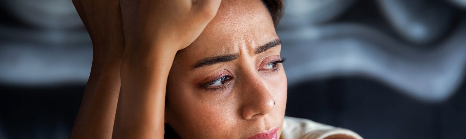 A sad woman considers her hidden trauma and stares sadly away.