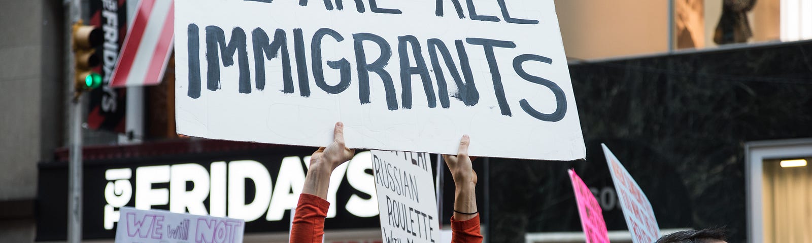 Photo of woman holding sign reading “We are all immigrants” at the Women’s March in New York, NY, January 22nd, 2017.