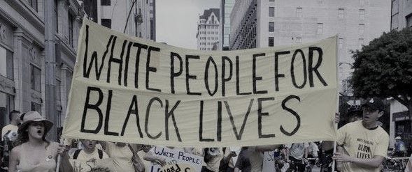 Image of people carrying a yellow banner that says “White People 4 Black Lives” in black writing.