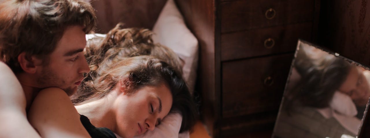 Two people snuggled in bed