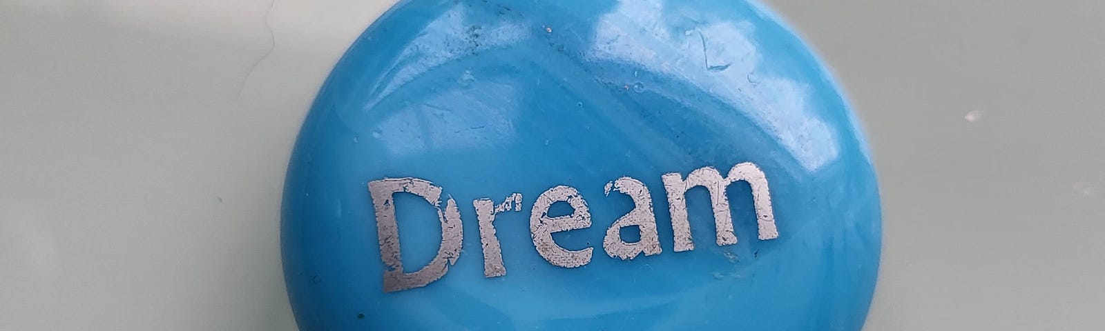 A blue stone with the word dream etched onto weight