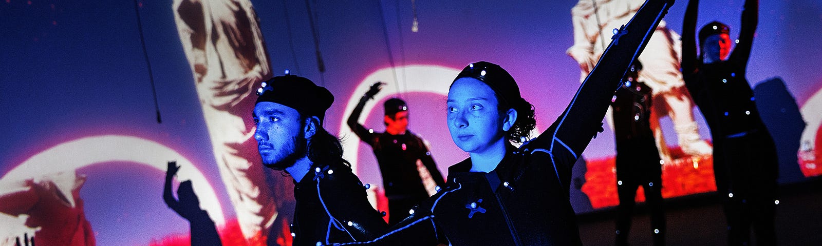 Isaiah Griffith and Marley Hewitt, second-year students in the Carson Emerging Media Arts program, pose in Mo-Cap (motion capture) suits with a group of students being filmed. The suits with their infrared sensors (round dots vecroed to the suit) allow a ring of cameras to turn their motion into animated characters on screen.