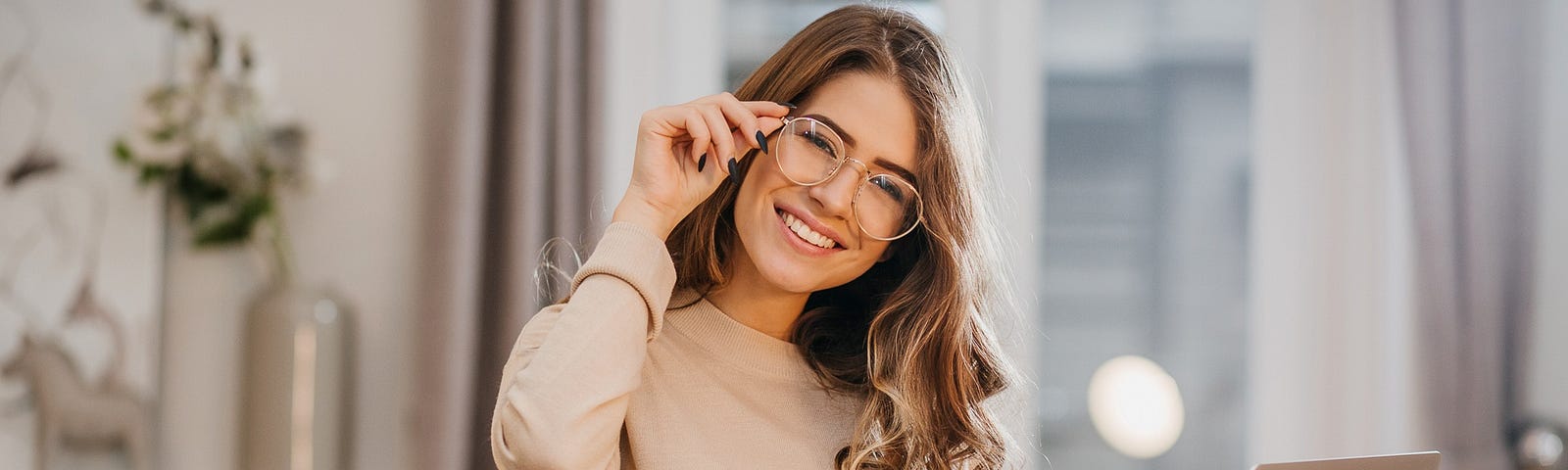 A smart person is standing in a room with a laptop in her hands.