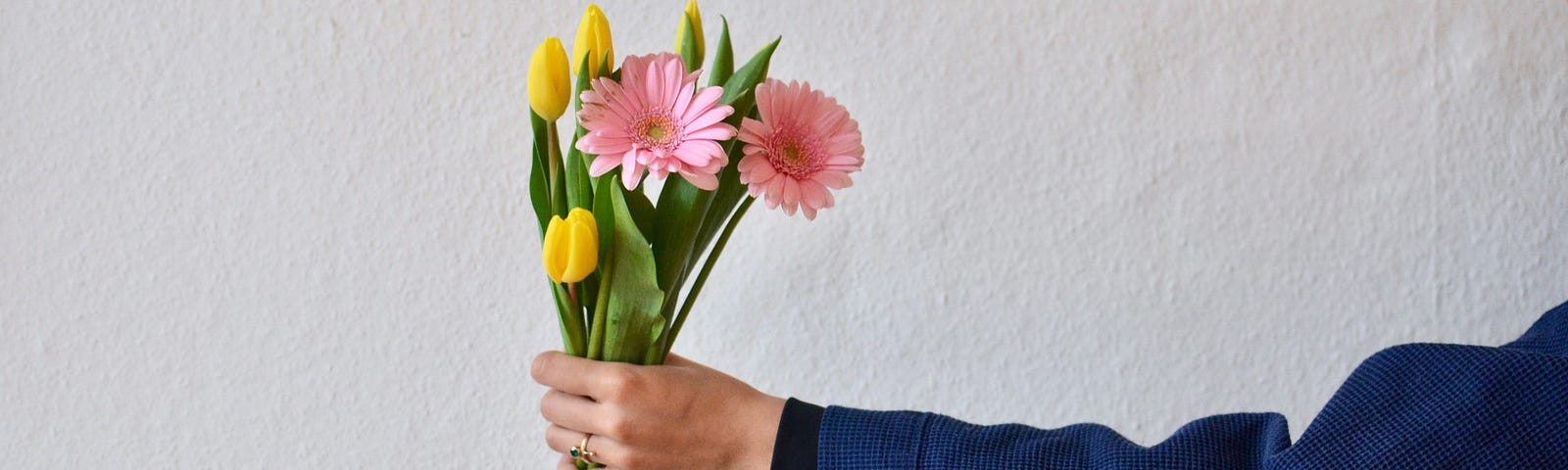 A hand holding out a small bouquet of flowers.