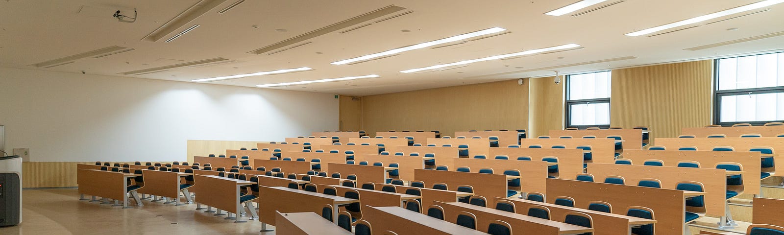 An empty university lecture room large enough for 100 students.  The lights are on waiting for the students to arrive.