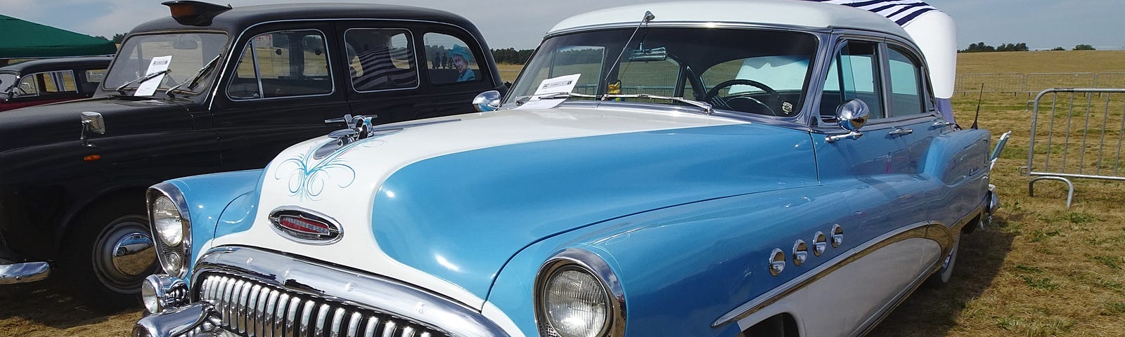 A 1953 Buick Sedan which was famous for having a V8 engine parked in a field at a car show. It is very similar to the Buick my brother and I used to work on together.