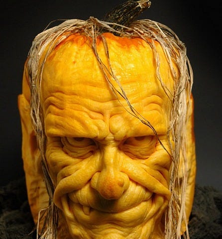 Sculpted pumpkin — yellow skin, straw hair hanging down, eerie eyes staring