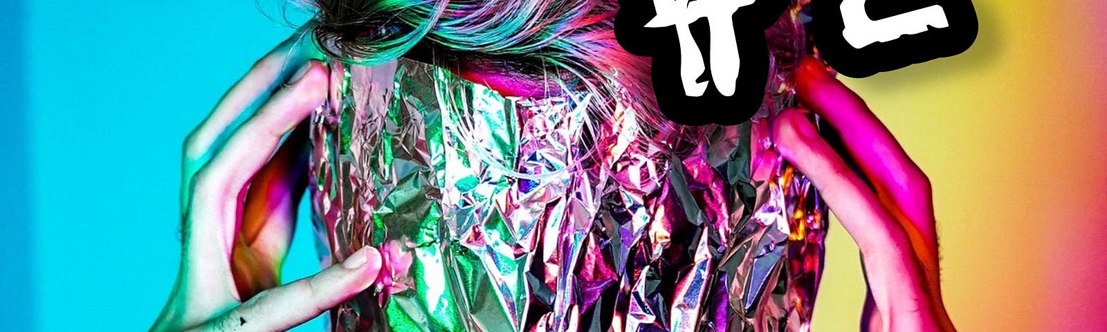Close-up of a person with tin foil wrapped around their head and face, with both hands/fingers at either side of their head as though they’re holding the foil on or have a headache. Rainbow multi-colored background and overlapping text heading that says PART #2