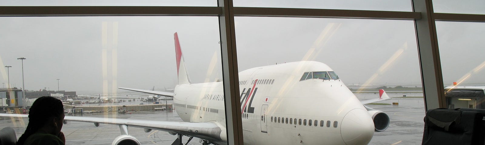 View of the JAL plane through the terminal window at JFK International Airport n NYC.