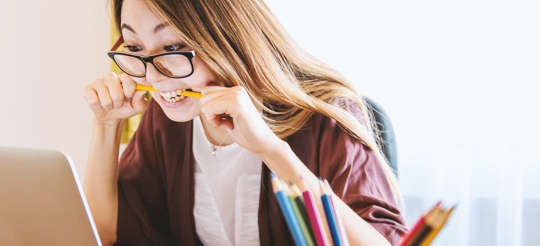 A frustrated freelancer sits at the computer and chews pencils.