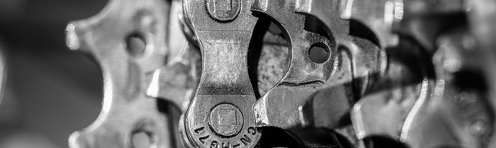 A black and white closeup of steel gears and a bike chain.