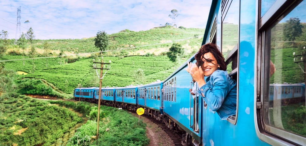 Picture of a lady traveling on a train through a beautiful landscape