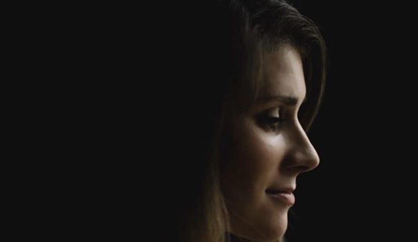 Photo of a white woman in profile in front of a black background.