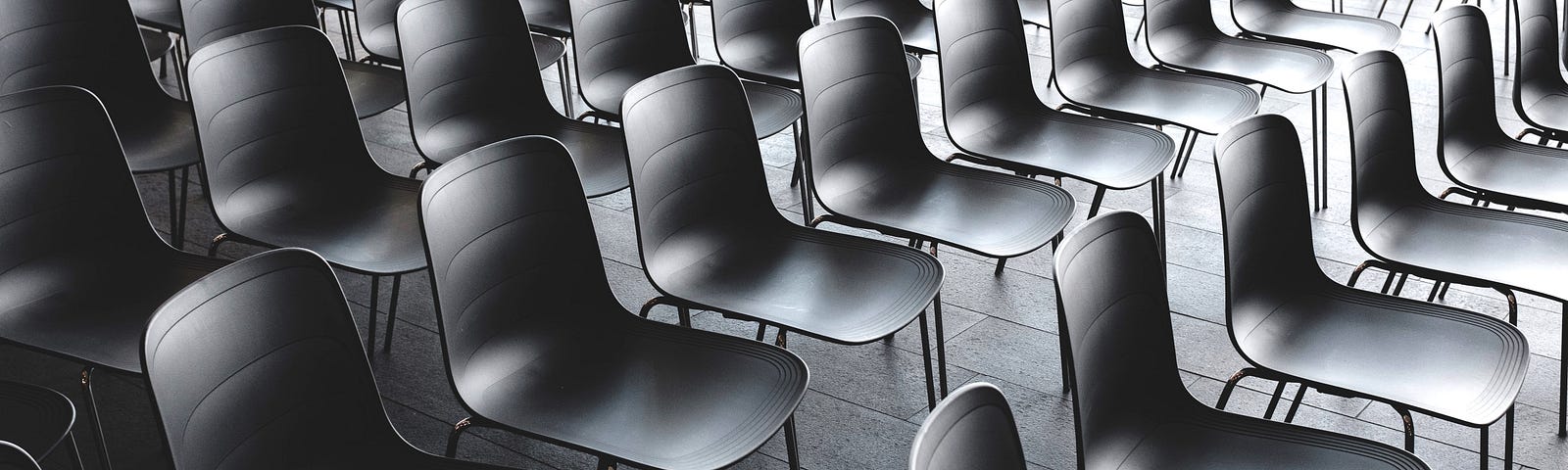 Many rows of black chairs behind each other.