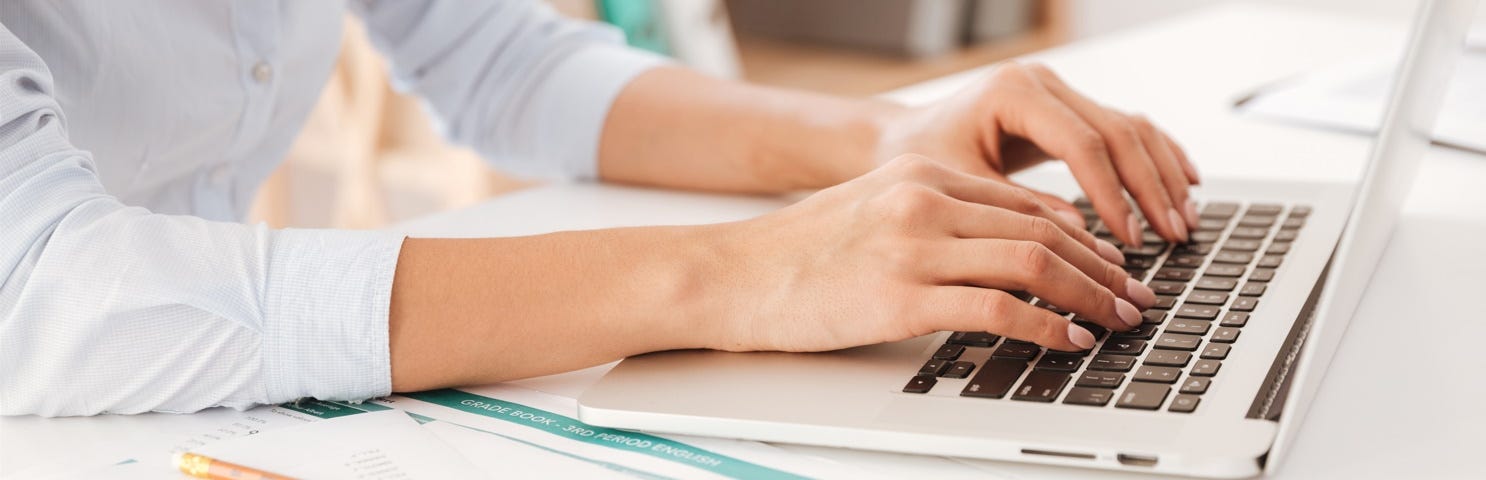 A writer is typing on their keyboard of their notebook computer.