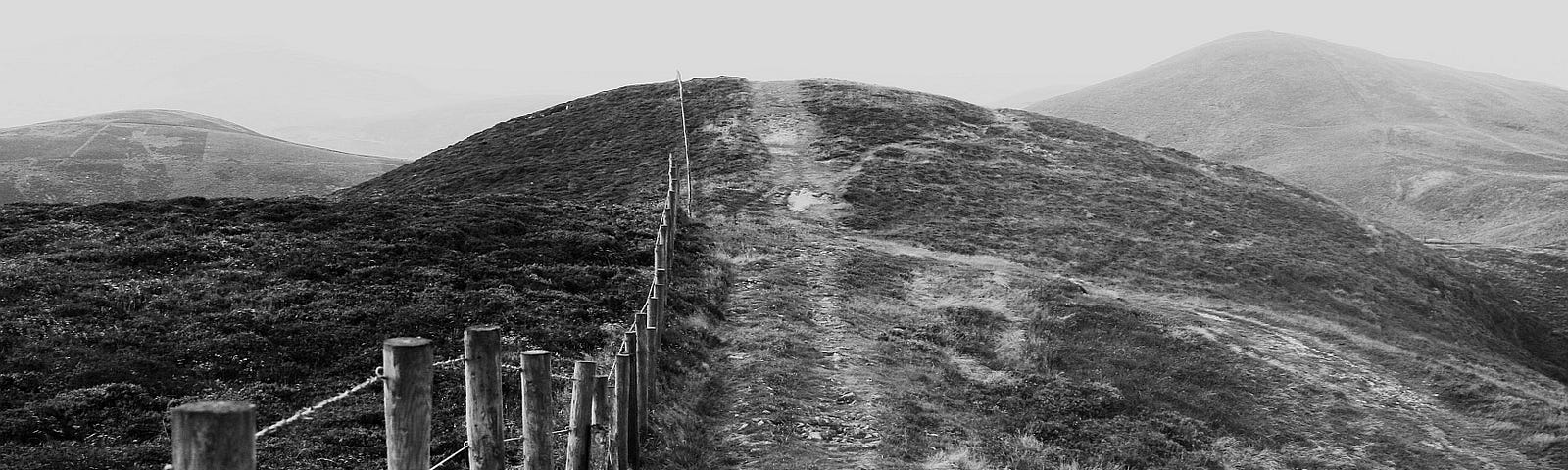 black and white photo of a fence and a hill