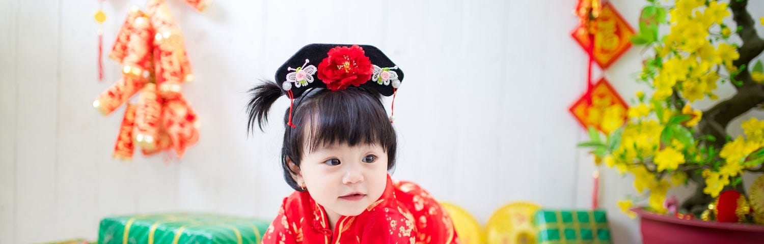 A Chinese baby girl wearing traditional clothes among presents.