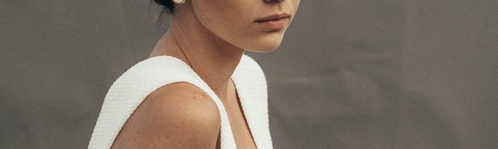 Young blonde woman in white dress looking sad.