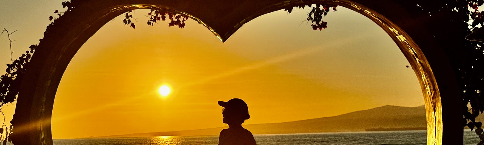 A picture of a woman framed by a large wooden heart. Gili Air Island, Indonesia. Photo courtesy of the author.