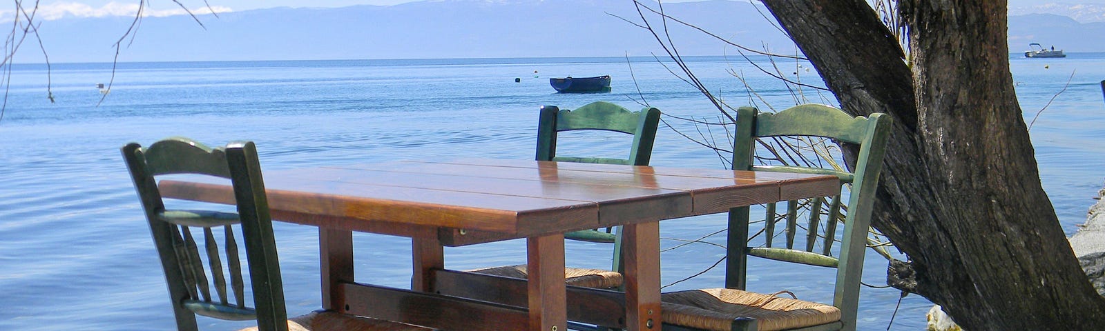 Table and three chairs by a lake.