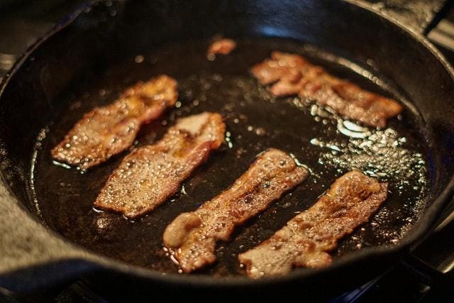 Bacon sizzling in cast iron pan.