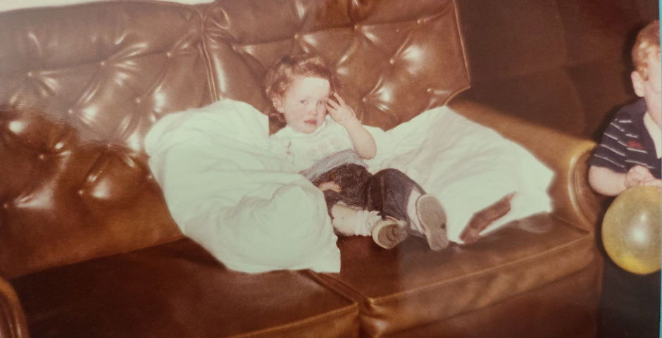 Author, a young redhaired girl, sitting on a brown sofa with bandage on head