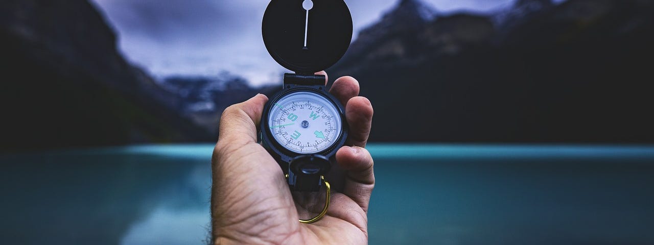 A man’s hand holding a compass.