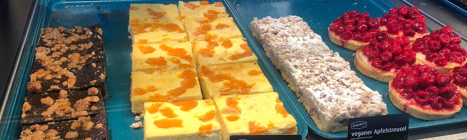 A selection of pastries in an Augsburg, Germany bakery. Products have a German product description on black placards.