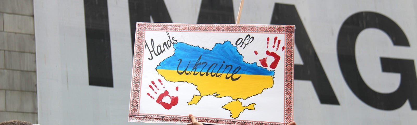 Woman holding a sign reading “hands off Ukraine” during a demonstration.