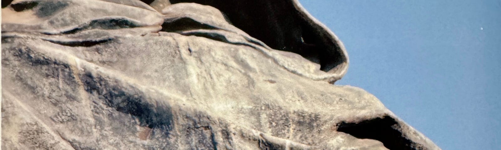 Photo of sculpture of Bruno, holding a Bible, with a somber face and hood over his head.