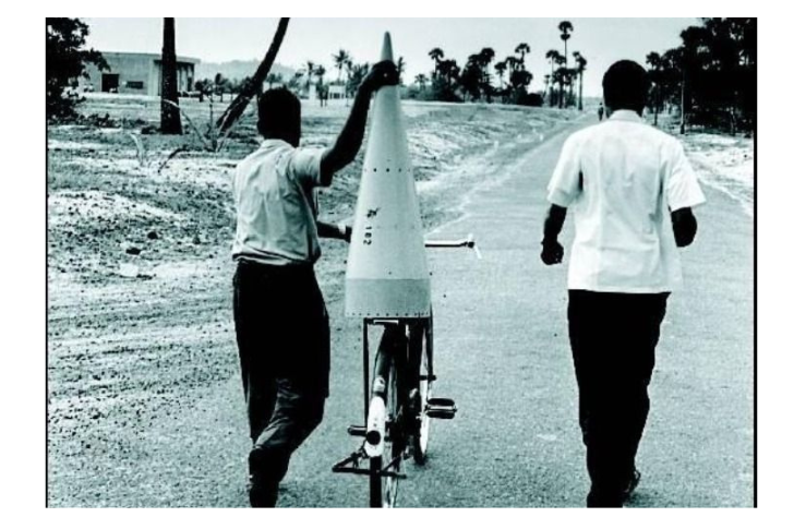 Two Indian space researchers carrying a piece of cone head of rocket by cycle in mid-1970s at ISRO rocket launch site for some experiments
