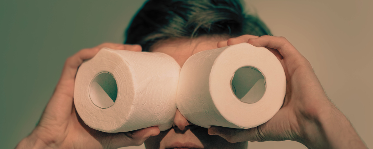 A man looking through toilet paper rolls.