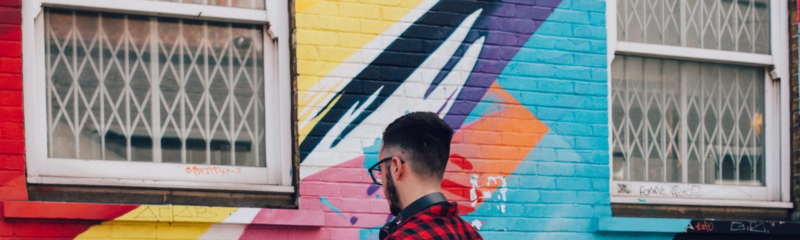 Image of man with a phone taking a photo of a colorful wall