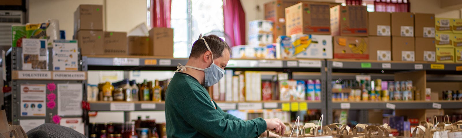 A volunteer organizes food in front of food bank shelves