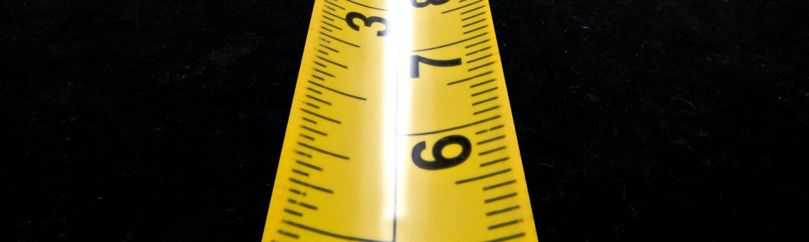 Yellow measuring tape on black background.