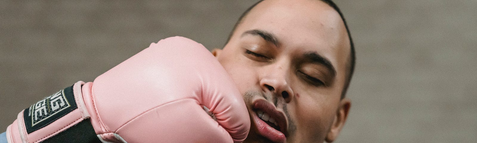 A man being punched in the face by a pink boxing glove