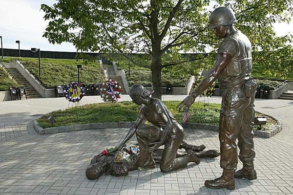 a bronze statue of a nurse and a soldier leaning over a wounded soldier on the ground — Vietnam veterans benefits