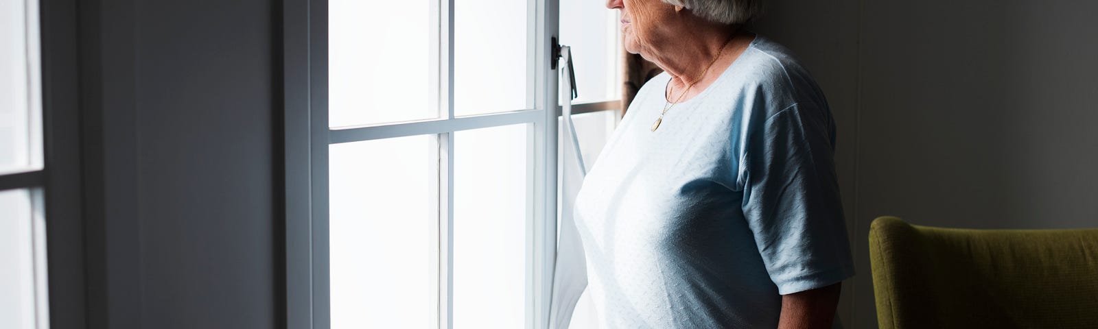 Photo showing an older woman looking out of the window, a concentrated expression on her face.