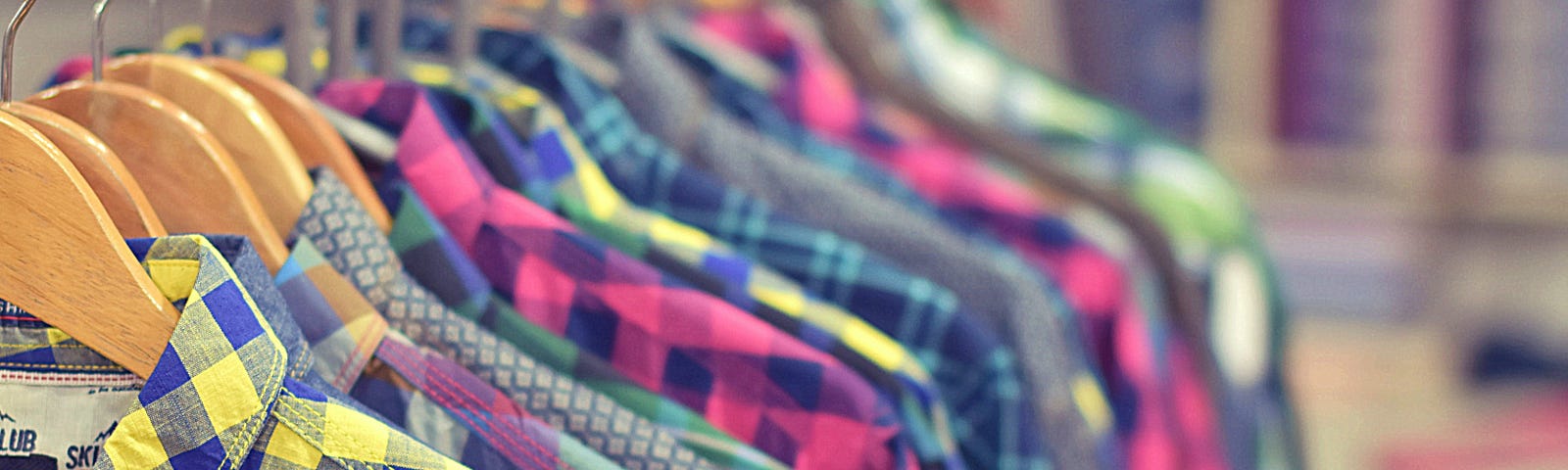 Assorted colorful plaid shirts hanging next to each other on a rack