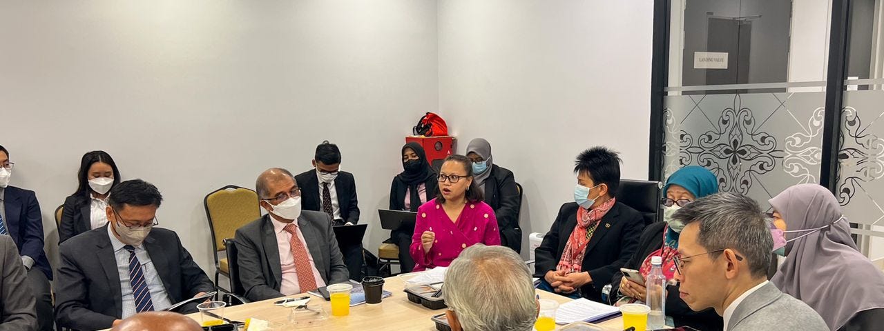 Individuals sitting around a table while Nadiah from KAMY is speaking. She is wearing a pink kebaya/baju kurung.