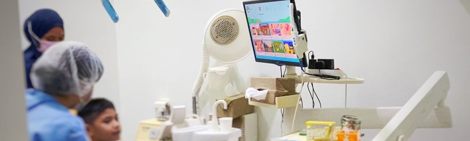 A child, dentist, and nurse. The child is seating on a dental chair.