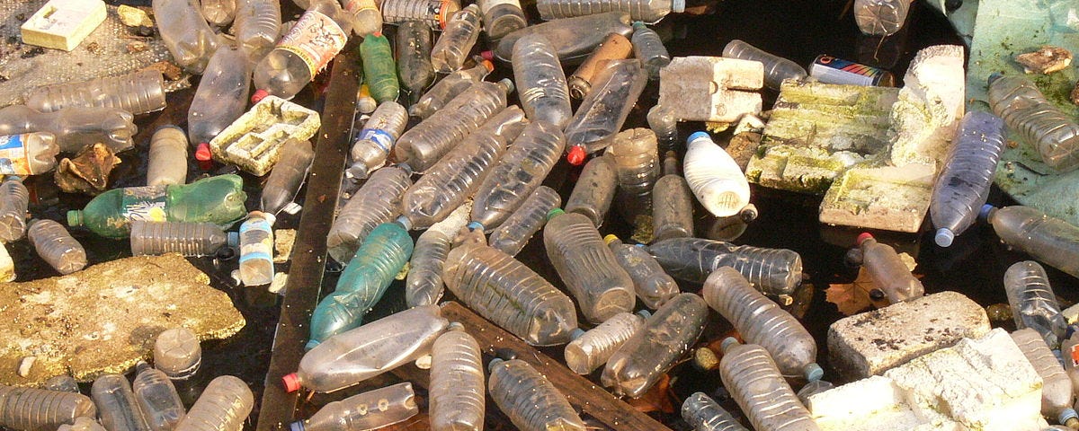 Dozens of plastic water bottles floating on a river.