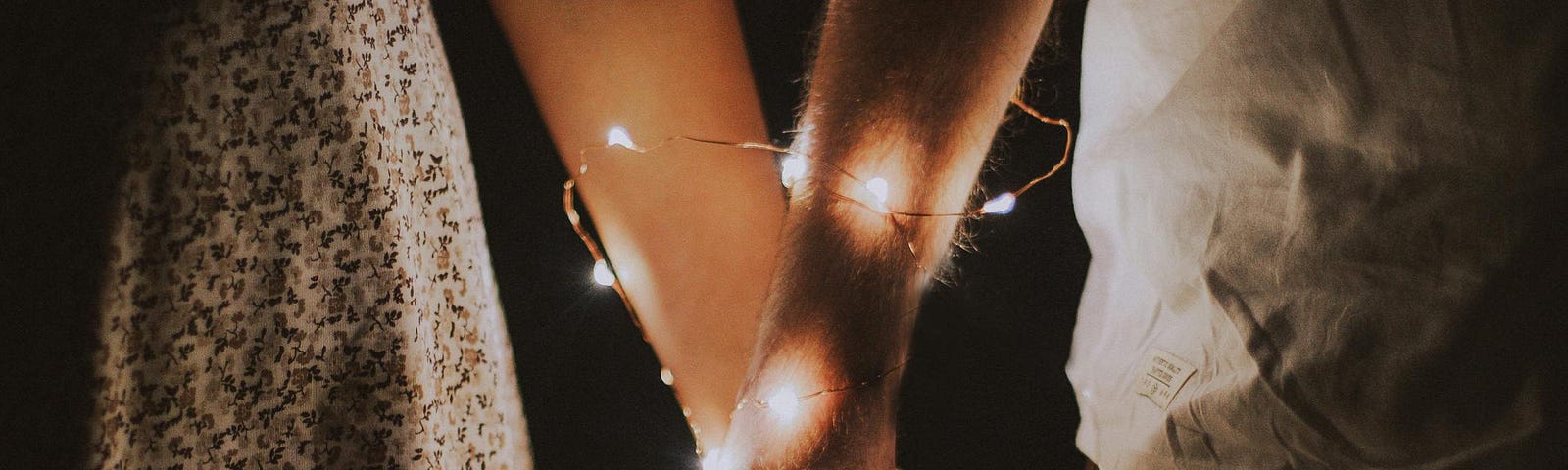A couple hold hands as tiny lights highlight their emotional and physical connection and how altruism lights up our lives.