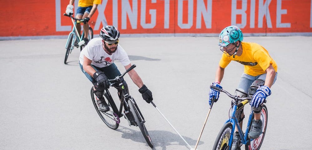 two bike polo players playing the ball