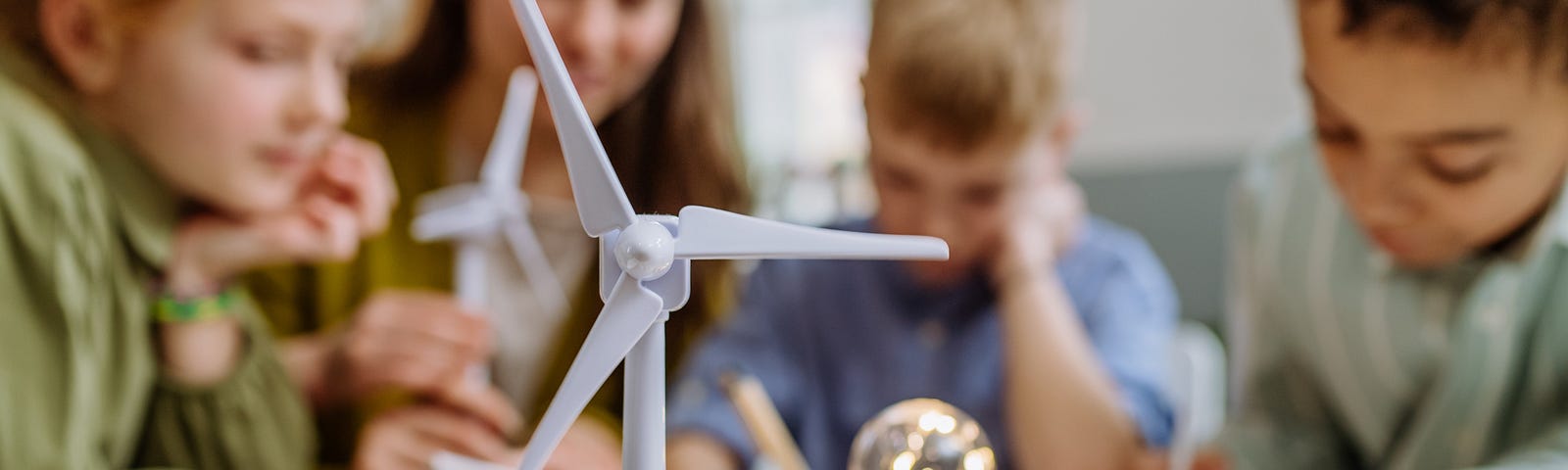 A teacher uses scale models of wind turbines to show children how wind can generate power