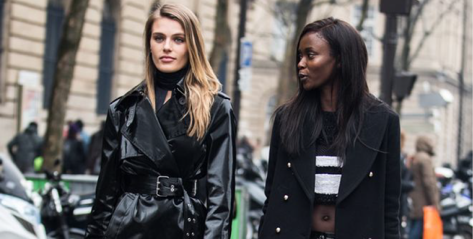 Two fashion models walking on the street with coats.