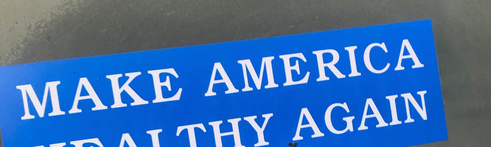 a blue bumper sticker with white letters reading “make america healthy again”