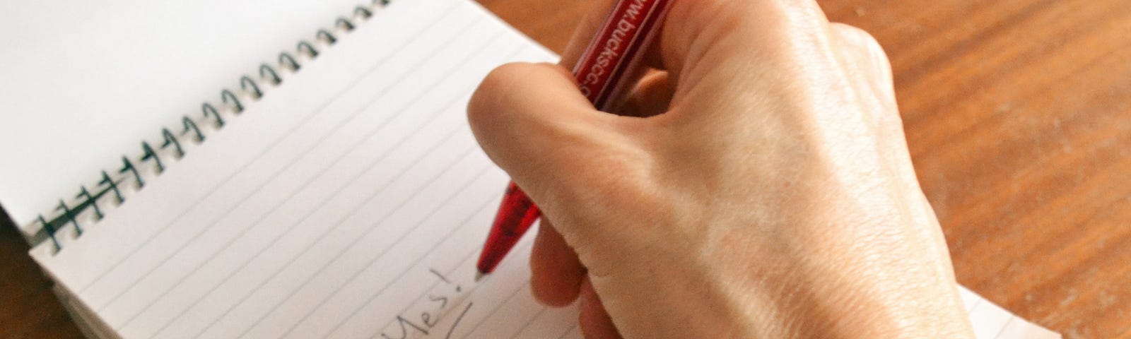 A hand scribbling on a notepad — image by author